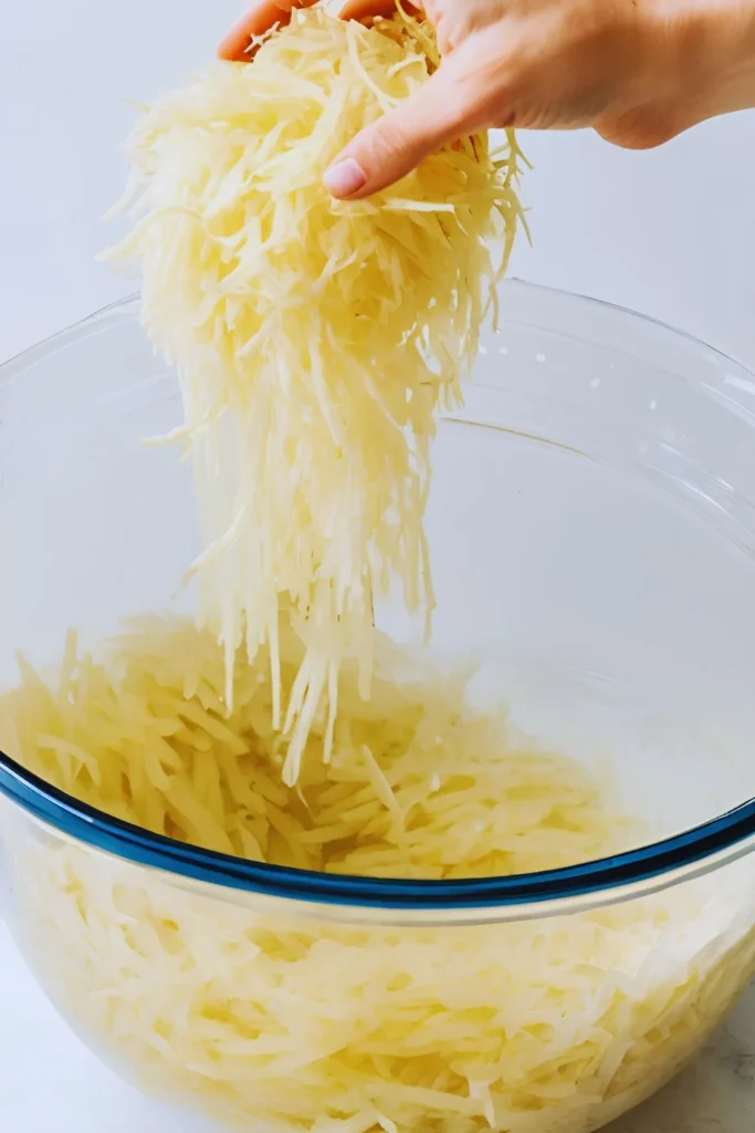 Shredded potatoes soaking in water for hash browns